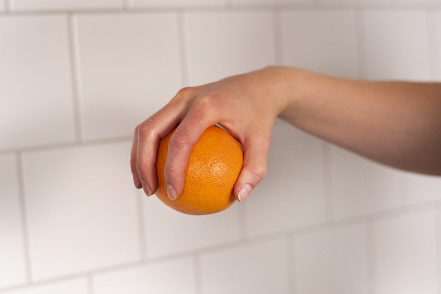Hand som håller i en apelsin.