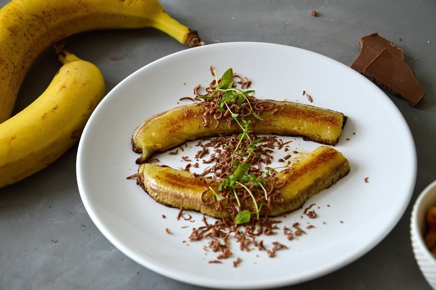 Bild på grillade bananer med choklad uppdukat på ett vitt fat.
