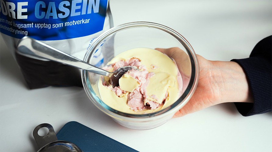 En hand som h�ller i en glassk�l med kaseinpudding med smak av hallon och vit choklad.