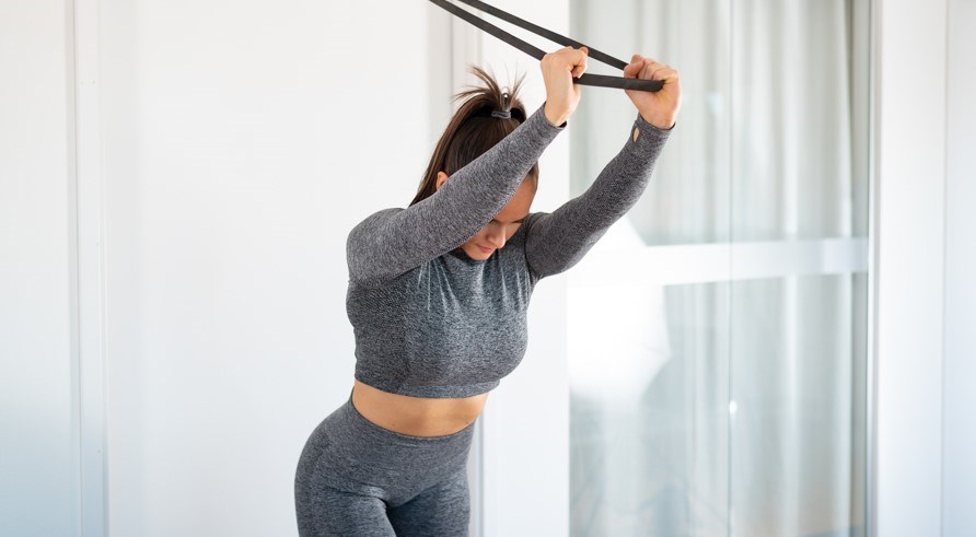 Kvinna gör övningen triceps push downs med gummiband. Kvinna gör övningen triceps push downs med gummiband.