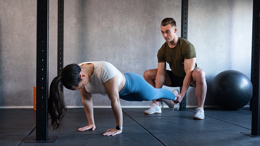 Man och kvinna som gör övningen squat push up.