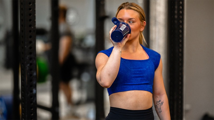 Kvinna dricker ur en shaker. 