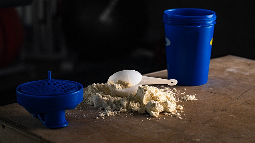 En shaker och en skopa med proteinpulver.