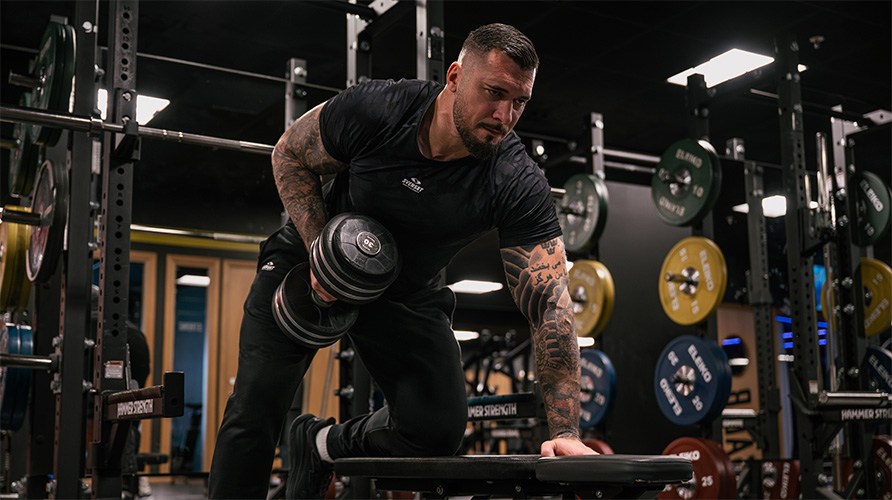 En man utf�r �vningen hantelrodd.