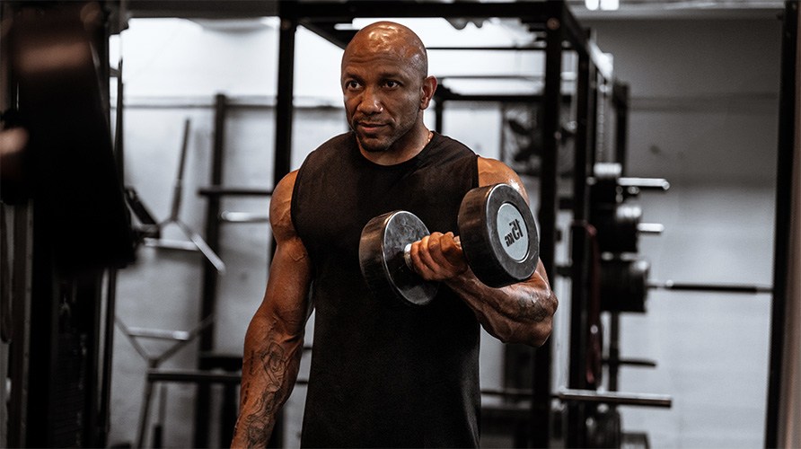 En man k�r tr�nings�vningen bicepscurl med hantel. 