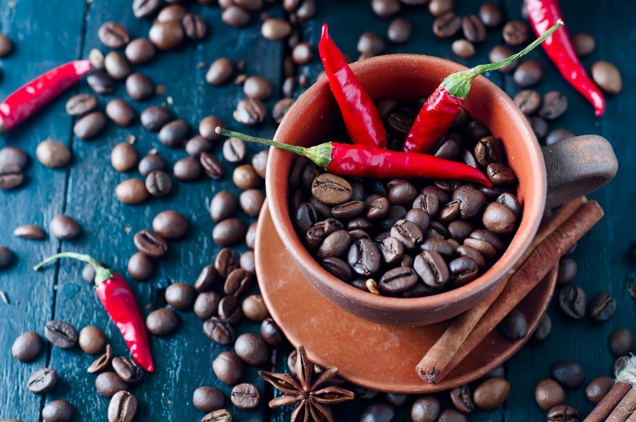 Kaffebönor och röd chili upplagt i en skål samt utspritt bredvid.