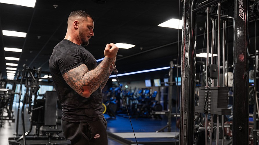 En man utf�r bicepscurl i kabelmaskin p� gym.